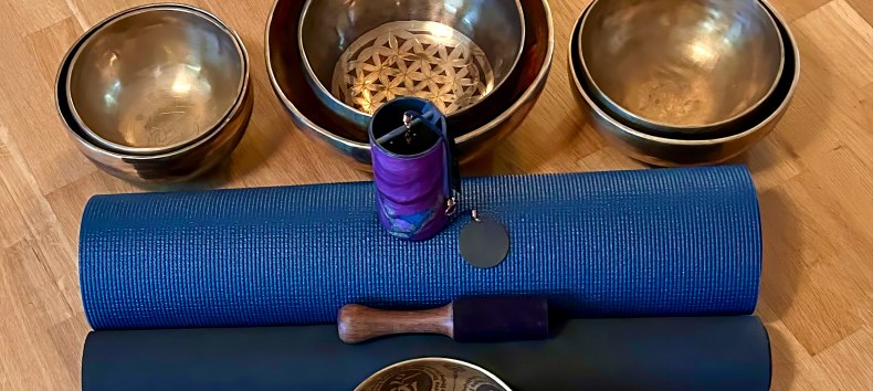 Setup f&uuml;r eine heilsame Auszeit: Traditionelle Klangschalen und sanfte Klangspiele stehen auf blauen Yogamatten bereit f&uuml;r die n&auml;chste meditative Chakren-Klangreise. Vorbereitung f&uuml;r tiefe Entspannung und Harmonisierung der Energiezentren. // &copy; Sandra Dethier