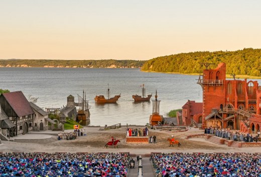 B&uuml;hne der St&ouml;rtebeker Festspiele in Ralswiek auf R&uuml;gen mit Publikum, mittelalterlichen Kulissen und Blick auf die Ostsee.