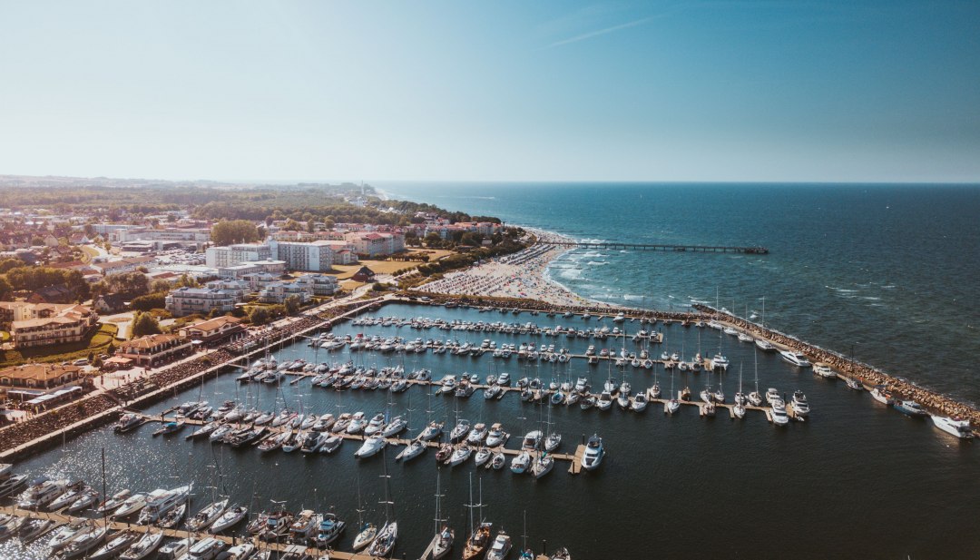 Luftaufnahme vom Yachthafen K&uuml;hlungsborn mit Booten, Strand und Ostsee bei Sonnenschein.