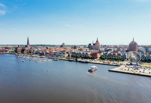 Van bovenaf ziet de stadshaven van Rostock eruit als een miniatuurwonderland. Zelfs het reuzenrad lijkt opeens niet meer zo groot. De excursieboot vaart rustig naar de steiger om nieuwe passagiers op te pikken. // &copy; MV-T/G&auml;nsicke