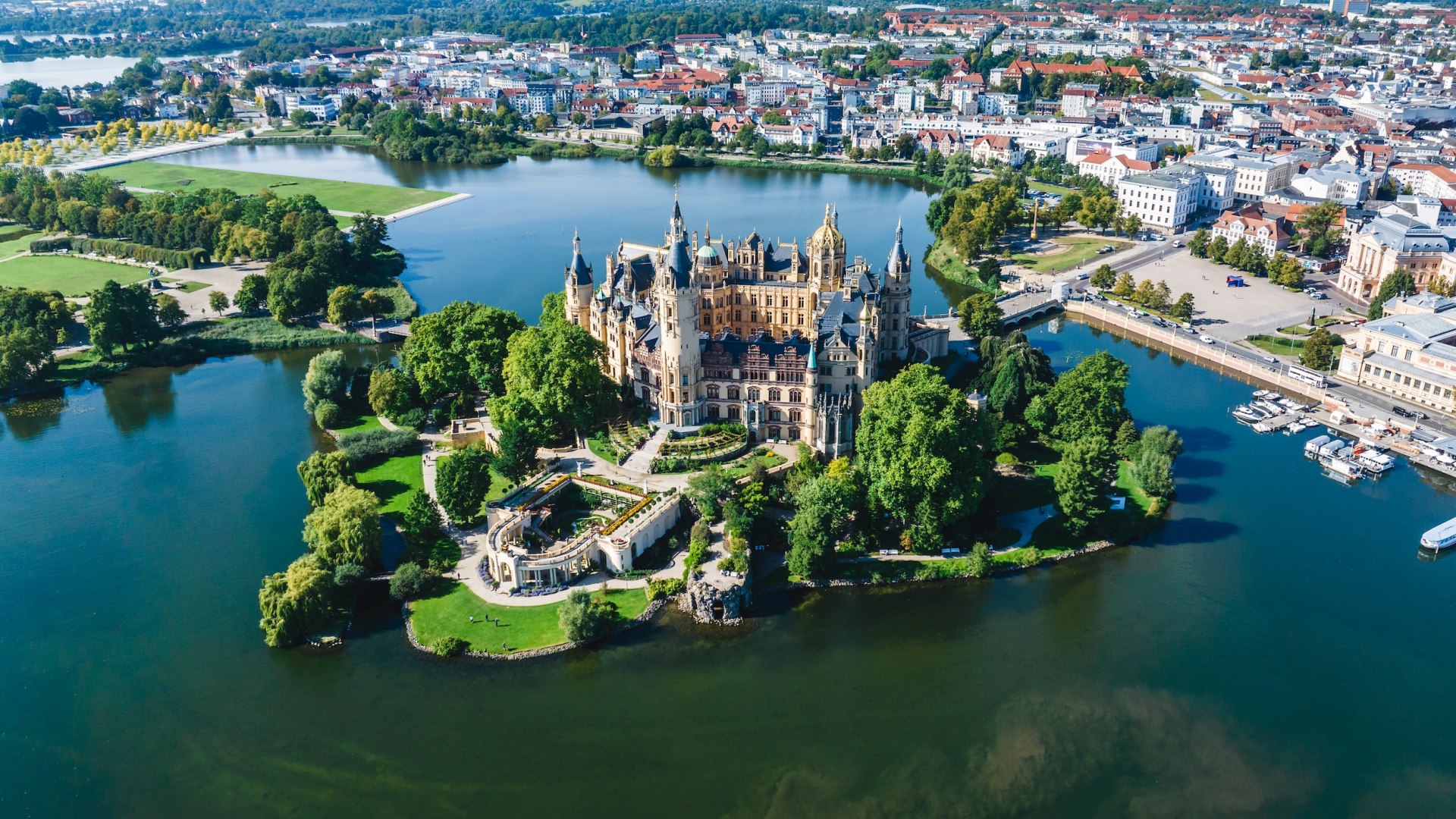 Das Schloss Schwerin aus der Luft im Sommer. Das Schloss steht auf einer kleinen Insel, umgeben von Wasser.