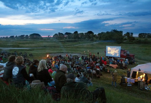 Freiluftkino in malerischer Landschaft: Zahlreiche Besucher genie&szlig;en eine Filmvorf&uuml;hrung unter freiem Himmel. // &copy; Tobias Rank
