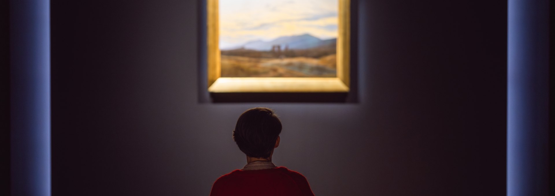 Een bezoeker zit voor een romantisch landschapsschilderij in de galerij van het Pommers Staatsmuseum.