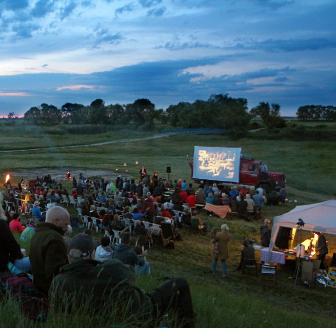 Freiluftkino in malerischer Landschaft: Zahlreiche Besucher genie&szlig;en eine Filmvorf&uuml;hrung unter freiem Himmel. // &copy; Tobias Rank