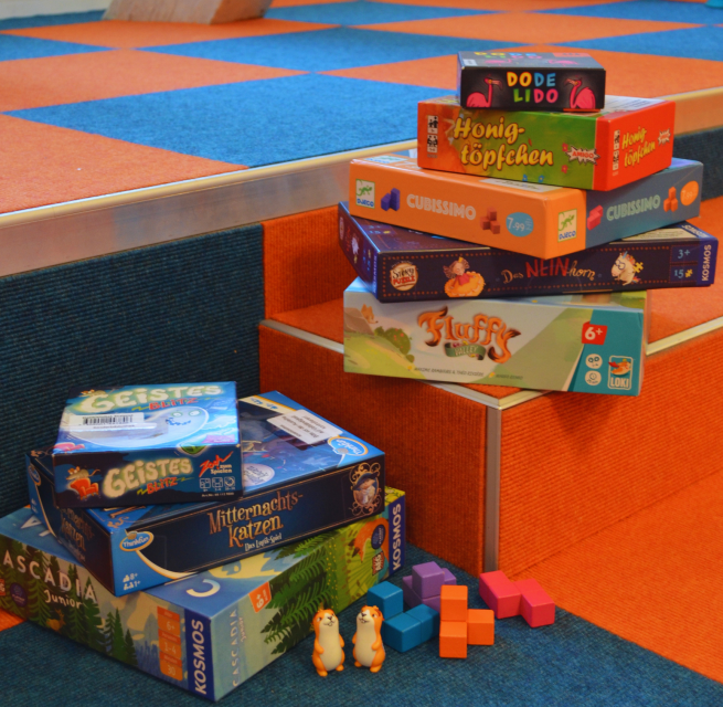 Viele verschiedene Gesellschaftsspiele wurden übereinandersgestapelt und Spielfiguren präsentiert. // © Stadtbibliothek Stralsund Viele verschiedene Gesellschaftsspiele wurden übereinandersgestapelt und Spielfiguren präsentiert. // © Stadtbibliothek Stralsund