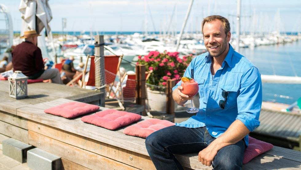 SOKO Wismar Kriminaloberkommissar Lars P&ouml;hlmann, alias Dominic Boeer, genie&szlig;t gern einen Cocktail im Bootshafen. // &copy; VMO, Alexander Rudolph