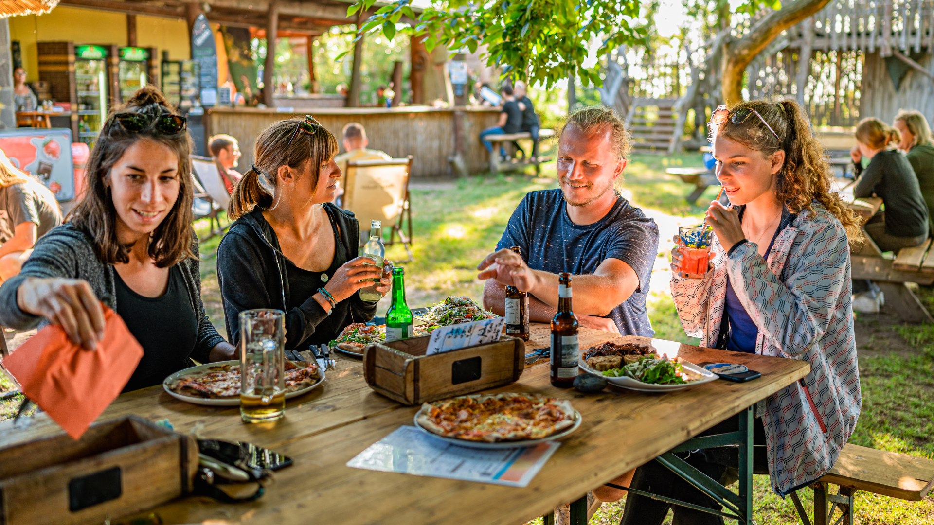 Stärkung mit Pizza, Sommerlimo, Bier und den beiden DeafVenture-Gründerinnen Pia und Marie in der „Tikibar“., © TMV/Tiemann Stärkung mit Pizza, Sommerlimo, Bier und den beiden DeafVenture-Gründerinnen Pia und Marie in der „Tikibar“.