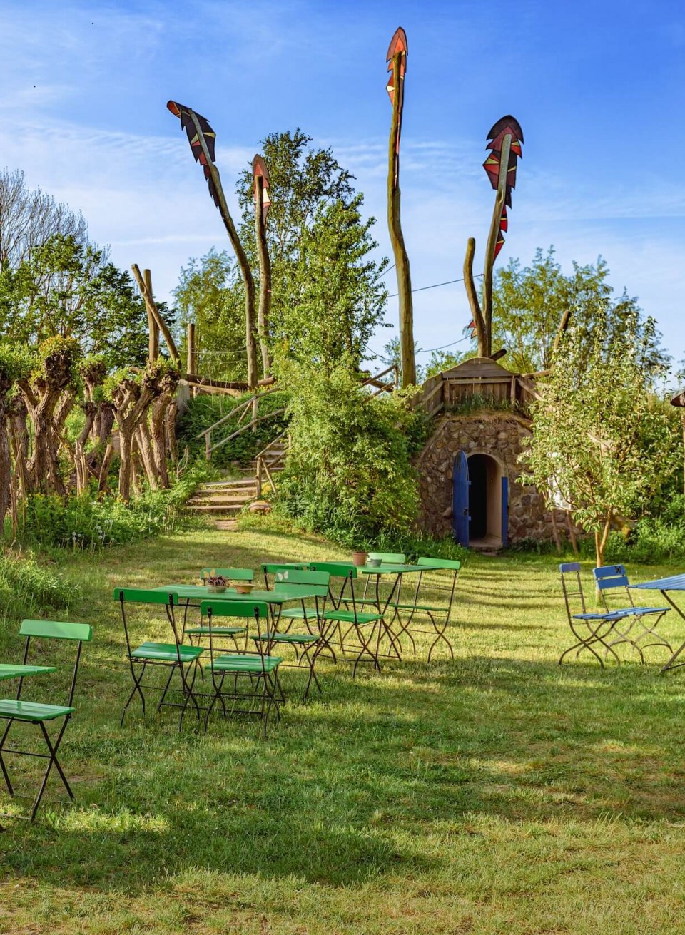 Wangeliner Garten und Café mit Holz und Stämmen die in die Luft ragen. Der Eingang zum Café aus Holz und in einer Steinwand die in einem Hügel verschwindet. // Im Wangeliner Gartencafé gibt es beides. // © MV-T/Tiemann Wangeliner Garten und Café mit Holz und Stämmen die in die Luft ragen. Der Eingang zum Café aus Holz und in einer Steinwand die in einem Hügel verschwindet.