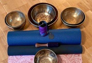 Setup f&uuml;r eine heilsame Auszeit: Traditionelle Klangschalen und sanfte Klangspiele stehen auf blauen Yogamatten bereit f&uuml;r die n&auml;chste meditative Chakren-Klangreise. Vorbereitung f&uuml;r tiefe Entspannung und Harmonisierung der Energiezentren. // &copy; Sandra Dethier