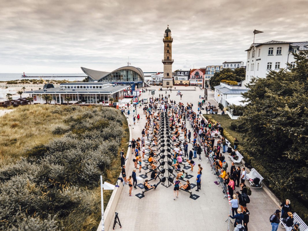 Roeiwedstrijd voor de vuurtoren van Warnem&uuml;nde op de promenade met roei-ergometers tijdens de fitnesswedstrijd Battle The Beach. // &copy; TMV/Witzel