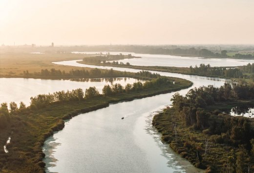 Ein Paar paddelt gemeinsam in einem Kanu &uuml;ber den Fluss die Peene in Mecklenburg-Vorpommern. Das Bild zeigt die Weite der Urlaubsregion Vorpommern.