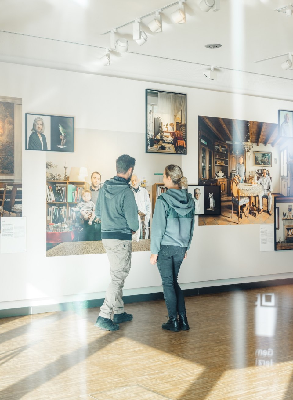 Zwei Besucher betrachten Fotografien an einer Wand in der Ausstellung des Max H&uuml;nten Hauses in Zingst.