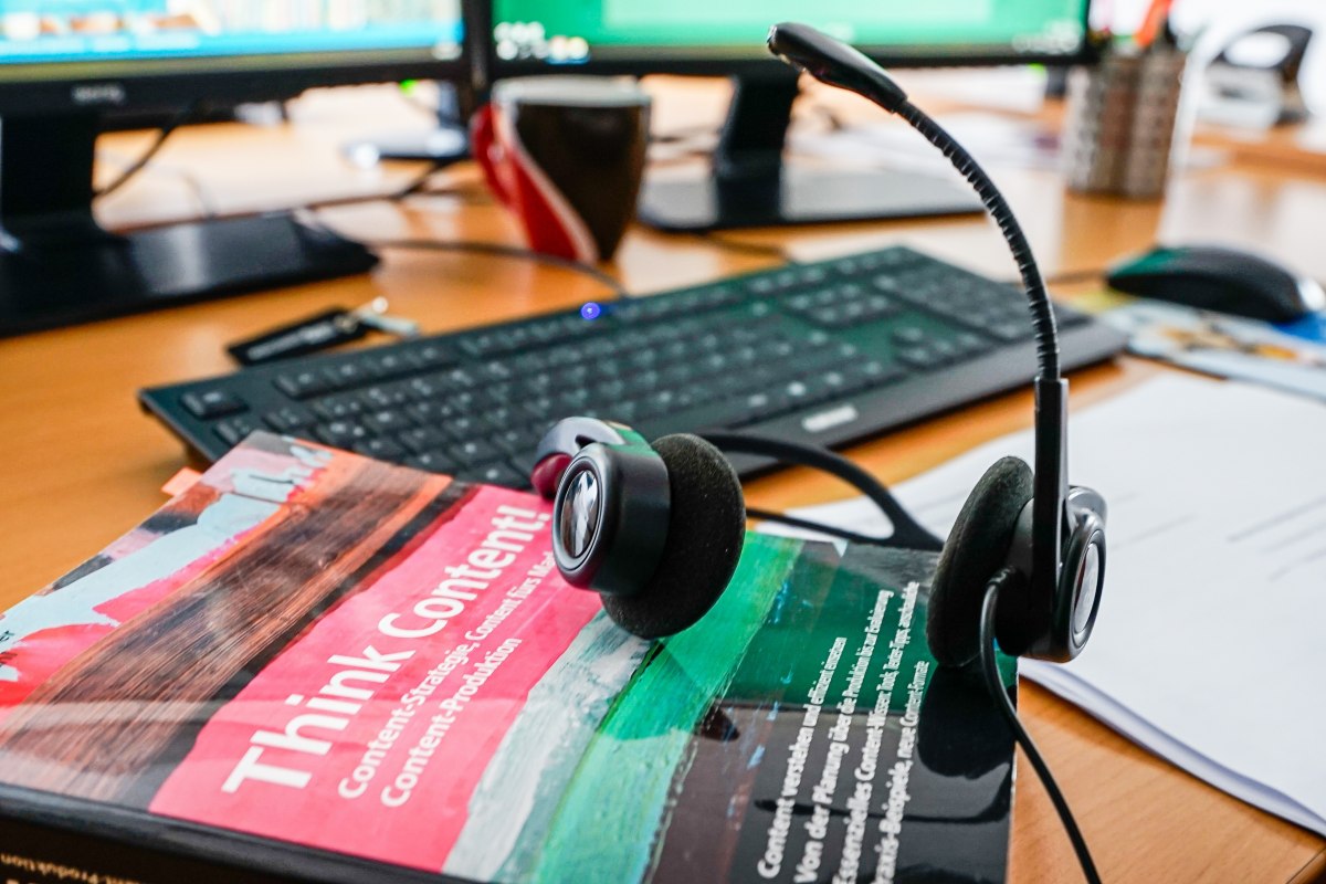 Ausschnitt eines Arbeitsplatzes mit Headset und Lehrbuch. // &copy; ahnithing photography