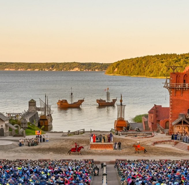 Bühne der Störtebeker Festspiele in Ralswiek auf Rügen mit Publikum, mittelalterlichen Kulissen und Blick auf die Ostsee.