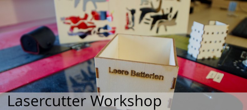 Gelaserte Box aus Sperrholz mit Beschriftung "Leere Batterien" im Hintergrund andere gelaserte Teile und der Lasercutter selbst, &copy; Hacklabor.de