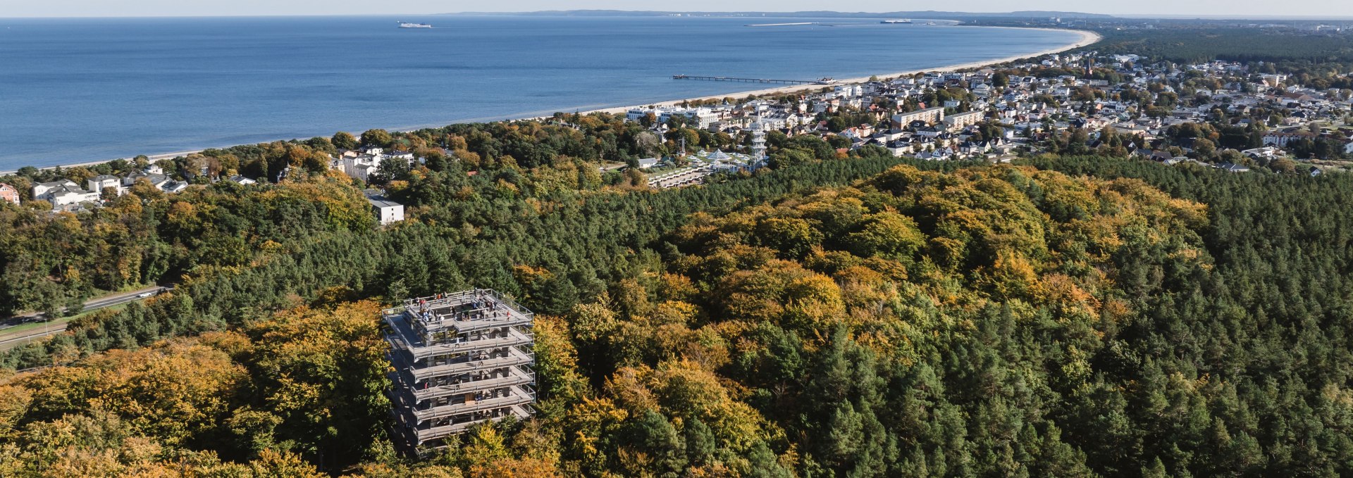 Luftaufnahme des Baumwipfelpfads Usedom im herbstlichen Wald mit Blick auf die Ostseeküste und die Stadt.