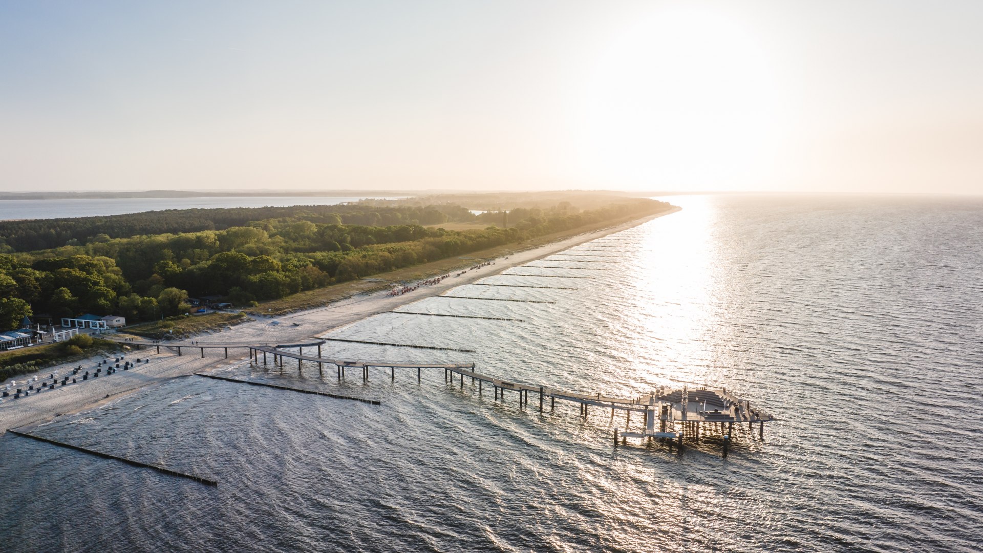 Luftaufnahme der Seebr&uuml;cke Koserow auf Usedom im warmen Licht des Sonnenuntergangs mit Strand und K&uuml;stenwald im Hintergrund.