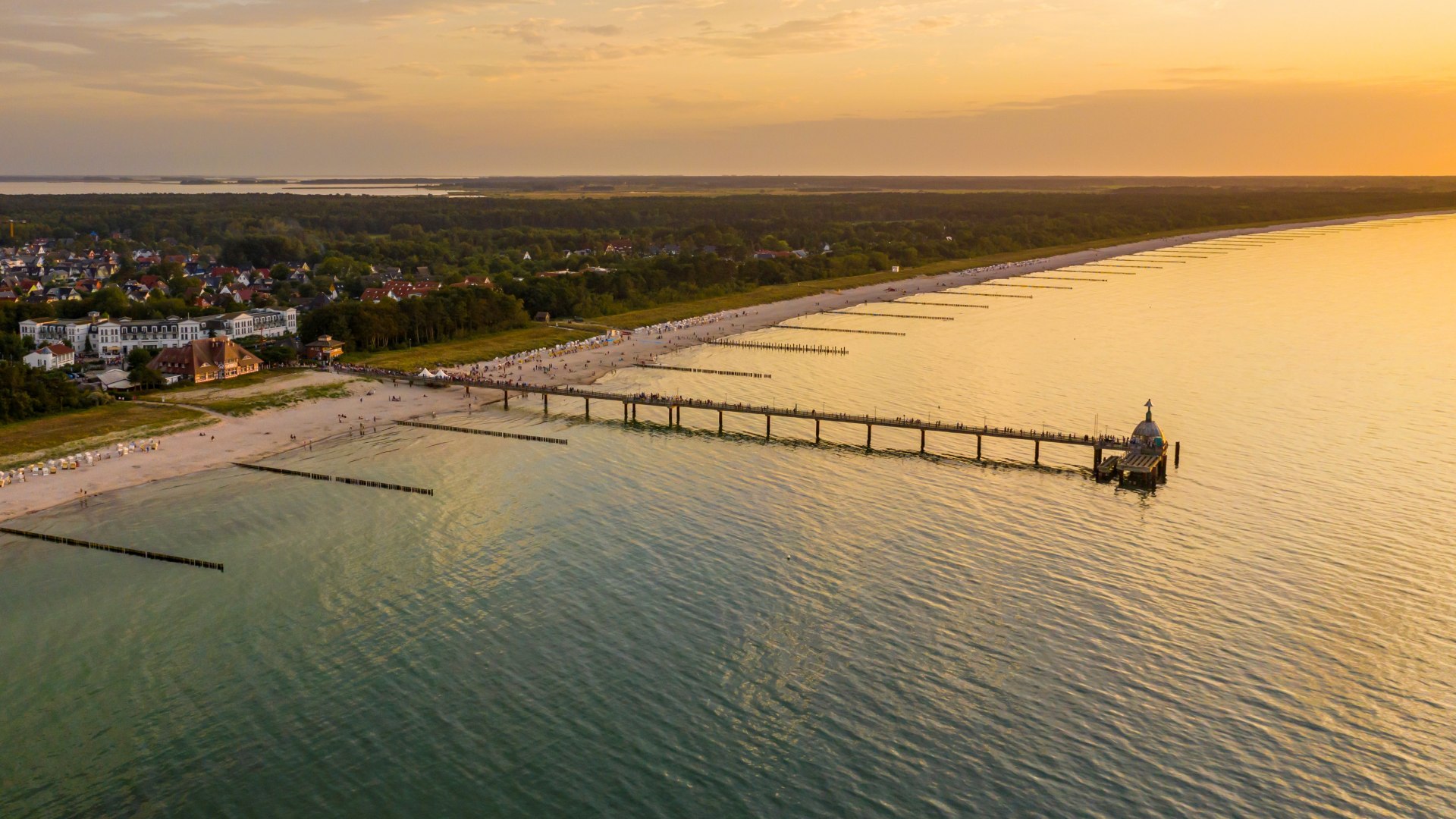 Luchtfoto van de pier van Zingst met uitzicht op het strand van de Baltische Zee en de ondergaande zon aan de horizon.