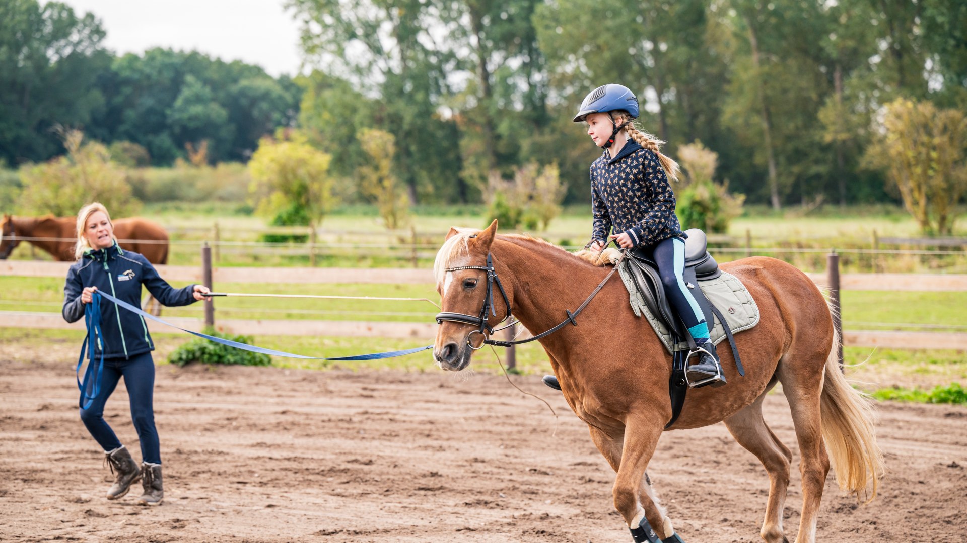 Ein Kind sitzt auf einem Pferd und wird im Kreis geleitet von der Reitlehrerin // Schnupperstunde auf dem Reiterhof Boltenhagen // © MV-T/Tiemann Ein Kind sitzt auf einem Pferd und wird im Kreis geleitet von der Reitlehrerin