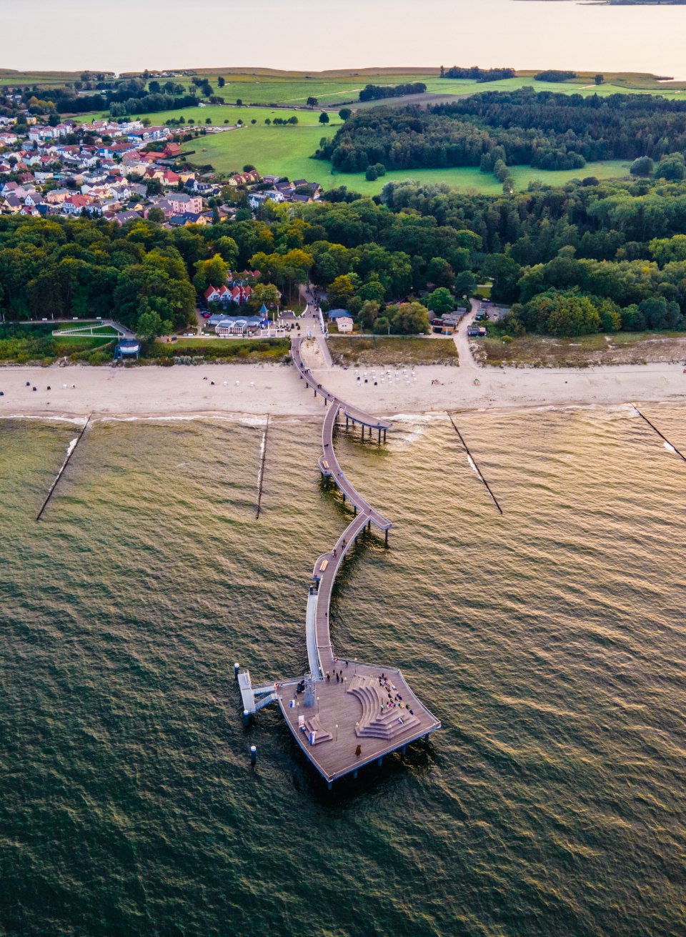 De pier van Koserow bij zonsondergang vanuit de lucht met uitzicht vanaf de Baltische Zee naar het strand