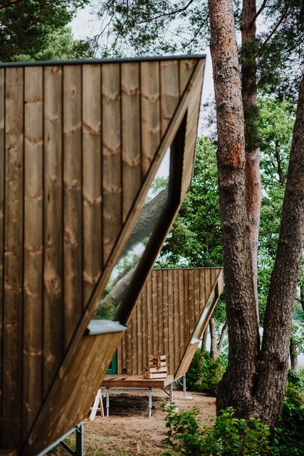 Minimalistisch wohnen, maximal entspannen – stilvolle Tiny Houses aus Holz bieten naturnahen Komfort für eine besondere Auszeit., © Ahoi Camp Canow Architektonisch moderne Tiny Houses mit Holzfassade und großen Panoramafenstern, eingebettet in einen Wald nahe eines Sees.