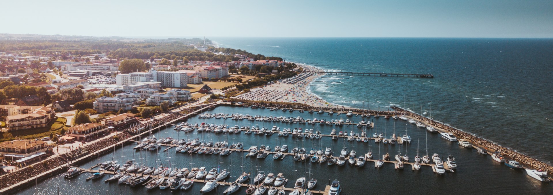 Luftaufnahme vom Yachthafen K&uuml;hlungsborn mit zahlreichen Booten und dem langen Sandstrand an der Ostsee.