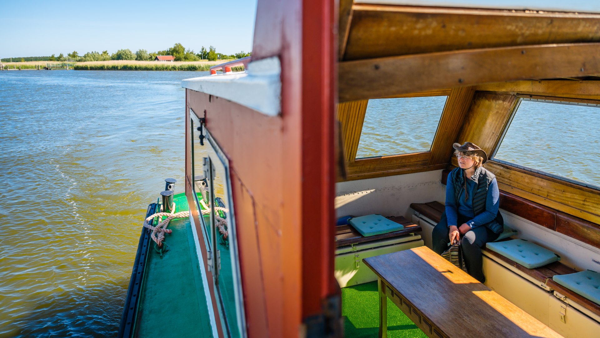 We nemen de boot naar het eiland van het Kirr vogelreservaat. Sylvia Juhnke zit in de boot en kijkt uit over de natuur.