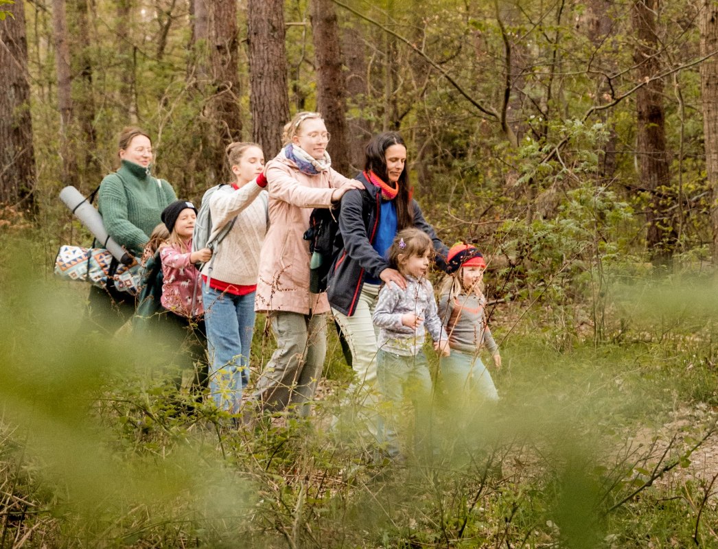 Kinderen en volwassenen genieten op dit moment van een bosbad. Ze lopen aandachtig en met gesloten ogen door een bos. // &copy; Christine D&ouml;rband / Langdock