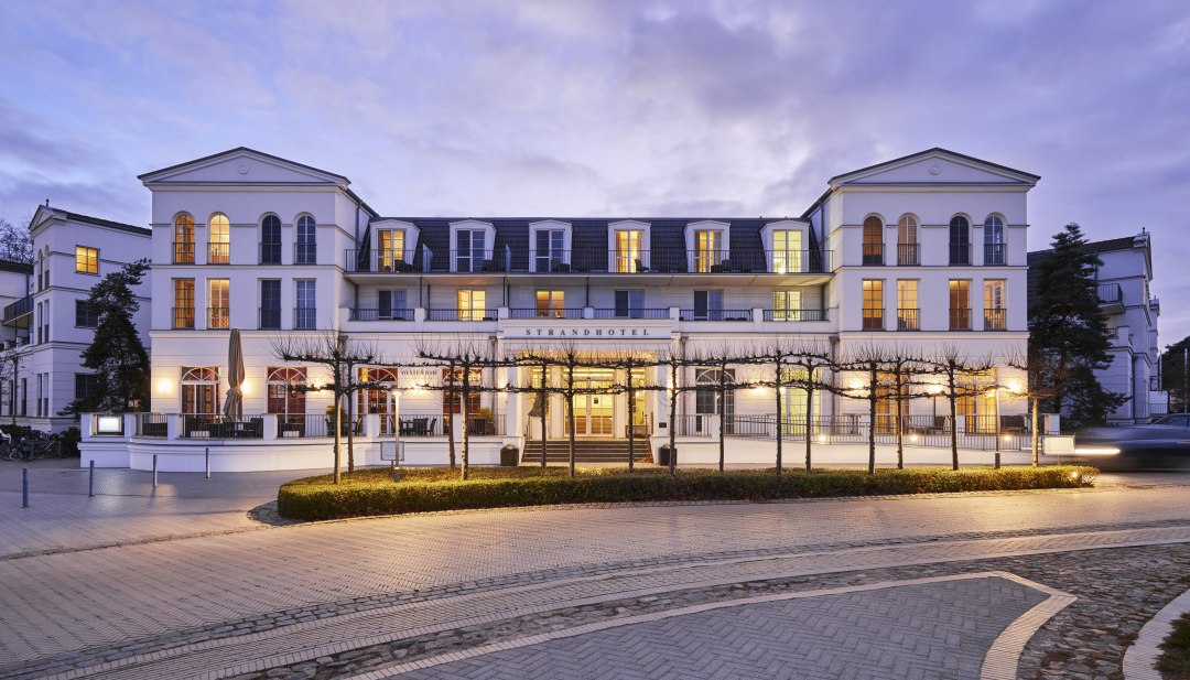 Verlicht Strandhotel Zingst in de stijl van kuurarchitectuur in de schemering, genomen vanaf de straatkant.