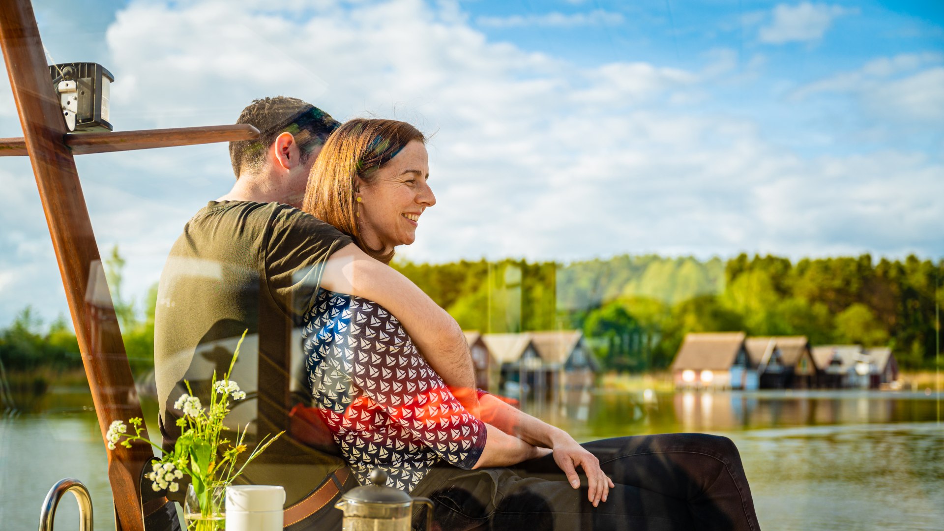 Een koppel zit op het dek van een woonboot en omhelst elkaar // Omdat de tieners het liefst bij elkaar blijven, hebben de ouders genoeg tijd om samen te genieten van wat quality time. // © MV-T/Tiemann Een koppel zit op het dek van een woonboot en omhelst elkaar
