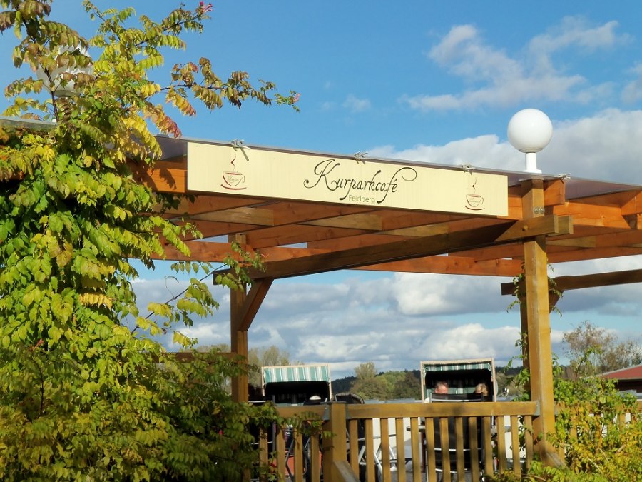 Blick von der Straße aus auf das Logo des Cafés mit Strandkörben im Hintergrund, © Tortenmarie Photo Blick von der Straße aus auf das Logo des Cafés mit Strandkörben im Hintergrund, © Tortenmarie Photo