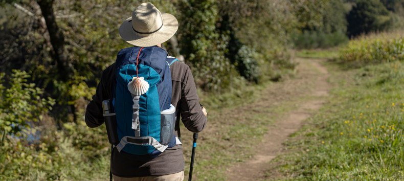 View from behind of a pilgrim walking on his way to Santiago de Compostela on a rural way. Way of saint james, Camino de Santiago // © AdobeStock View from behind of a pilgrim walking on his way to Santiago de Compostela on a rural way. Way of saint james, Camino de Santiago // © AdobeStock