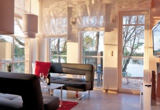 Wohnbereich der Ferienwohnung Fischadler mit gro&szlig;en Scheunenfenstern // &copy; Andre Pretzel