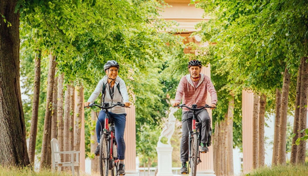 Mit dem Fahrrad durch Neustrelitz - ein Paar f&auml;hrt durch eine Allee