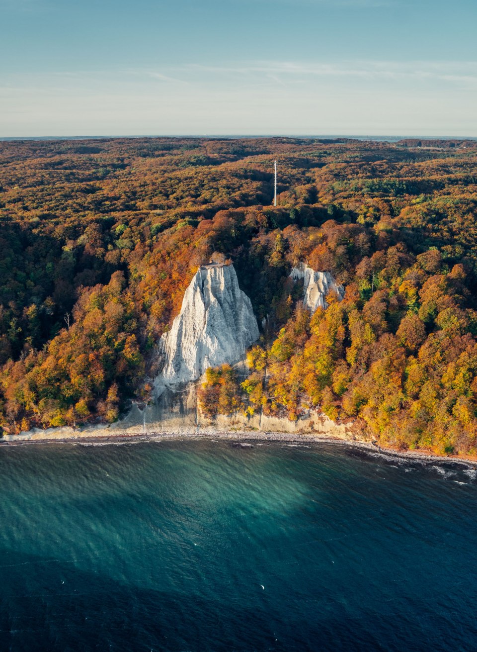 Die imposanten Kreidefelsen im Nationalpark Jasmund leuchten in der morgendlichen Herbstsonne, umgeben von einem Meer aus bunt gefärbtem Laub und der tiefblauen Ostsee – ein atemberaubender Anblick in der goldenen Jahreszeit. // © MV-T/Gänsicke Die imposanten Kreidefelsen im Nationalpark Jasmund leuchten in der morgendlichen Herbstsonne, umgeben von einem Meer aus bunt gefärbtem Laub und der tiefblauen Ostsee – ein atemberaubender Anblick in der goldenen Jahreszeit.
