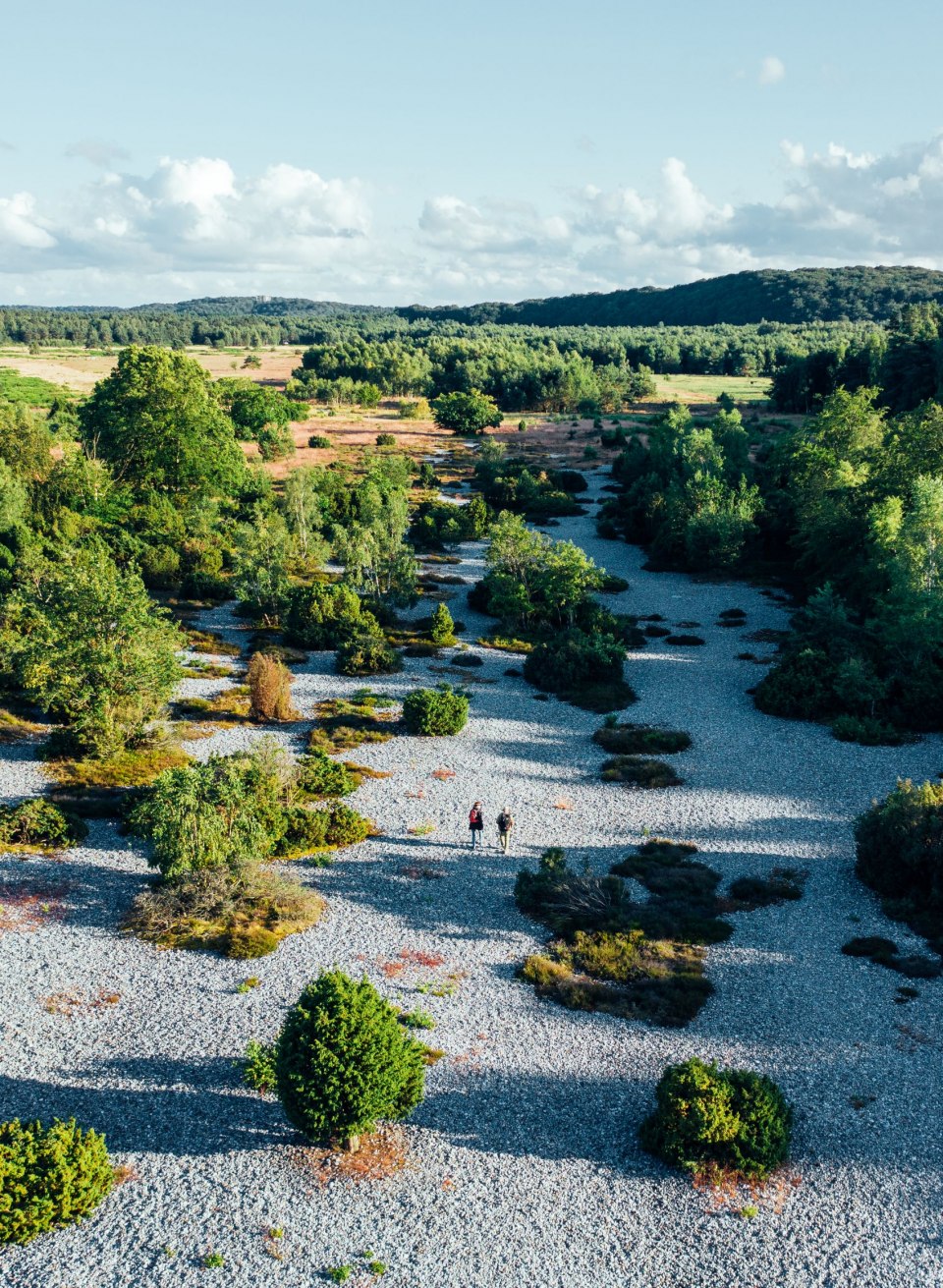 Vuursteenvelden bij Mukran op het eiland R&uuml;gen met grindvlakten, groene vegetatie en wandelaars midden op de heide.