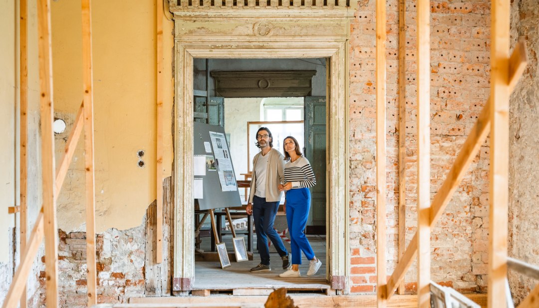 Twee mensen bekijken een tentoonstelling in het paleis van Ludwigsburg door een historisch deurkozijn met metselwerk.