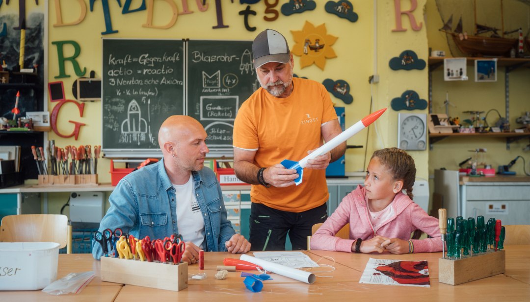 Een cursus in het Experimentarium in Zingst - iemand laat de constructie van een raket zien aan een vader en zijn dochter, die de raket moeten nabouwen. // Valea en haar vader leven zich creatief uit in het Experimentarium in Zingst en maken een raket. Laat de vakantie maar beginnen! // © MV-T/Petermann Een cursus in het Experimentarium in Zingst - iemand laat de constructie van een raket zien aan een vader en zijn dochter, die de raket moeten nabouwen.