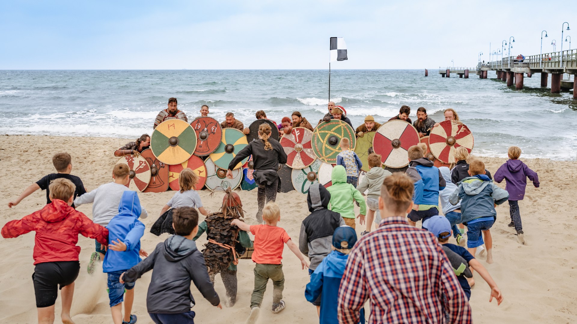 Eine Mauer aus Schildern gegen angreifende Kinder am Strand - das Wikingerfest in Göhren. // Großes Finale: Wenn Göhrener Kinder angreifen, sind auch Wikingerhorden überfordert. // © MV-T/Tiemann Eine Mauer aus Schildern gegen angreifende Kinder am Strand - das Wikingerfest in Göhren.