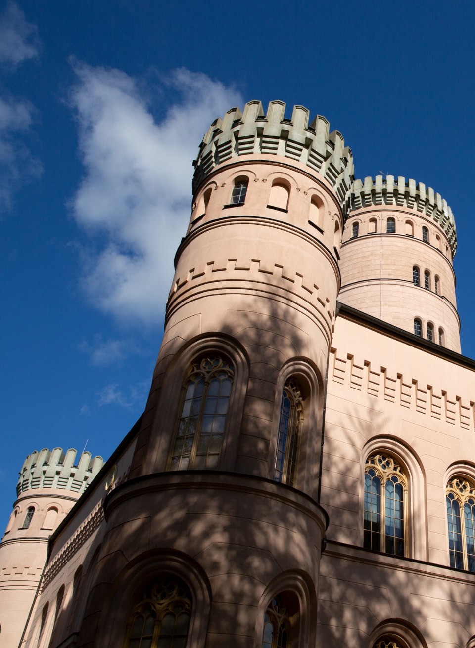 Jagdschloss Granitz auf Rügen mit runden Türmen und Zinnen vor blauem Himmel. // Detailaufnahme des prächtigen Jagdschlosses Granitz auf Rügen. Die runden Türme mit ihren markanten Zinnen ragen vor einem strahlend blauen Himmel empor. Das Sonnenlicht wirft leichte Schatten auf die sandfarbenen Fassaden und die kunstvollen Fenster. // © MV-T/Prast Jagdschloss Granitz auf Rügen mit runden Türmen und Zinnen vor blauem Himmel.
