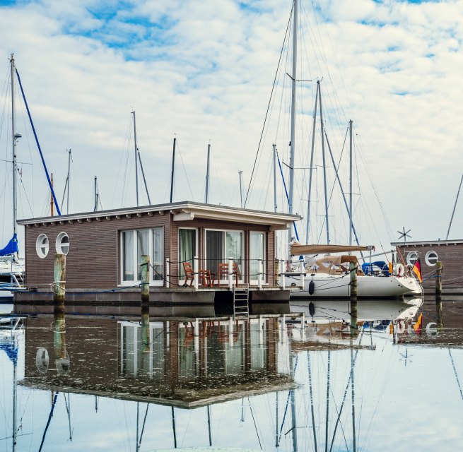 Schwimmendes Urlaubsglück: Die im Stil von Hausbooten konstruierten Suiten sind fest verankert., © TMV/Tiemann Hausboote und Segelboote liegen angeleint im Hafen von Krummin