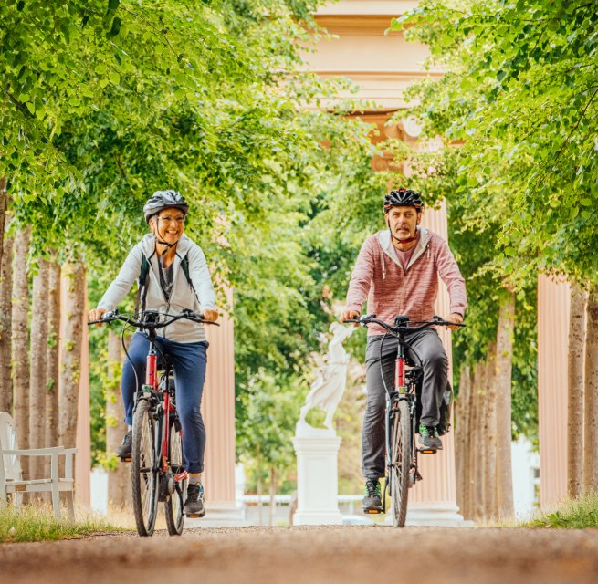 Mit dem Fahrrad durch Neustrelitz - ein Paar fährt durch eine Allee // Mit dem Fahrrad durch Neustrelitz entlang der Alleen // © MV-T/Tiemann Mit dem Fahrrad durch Neustrelitz - ein Paar fährt durch eine Allee
