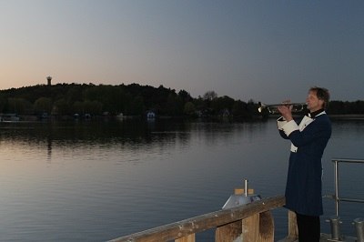 Trompetsolo met de heer Viehstädt in wachtersuniform aan de oever van de promenade langs het meer van Krakau // © Touristinformation Krakow am See Trompetsolo met de heer Viehstädt in wachtersuniform aan de oever van de promenade langs het meer van Krakau // © Touristinformation Krakow am See