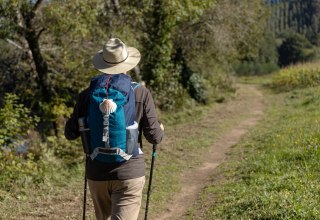 View from behind of a pilgrim walking on his way to Santiago de Compostela on a rural way. Way of saint james, Camino de Santiago // &copy; AdobeStock