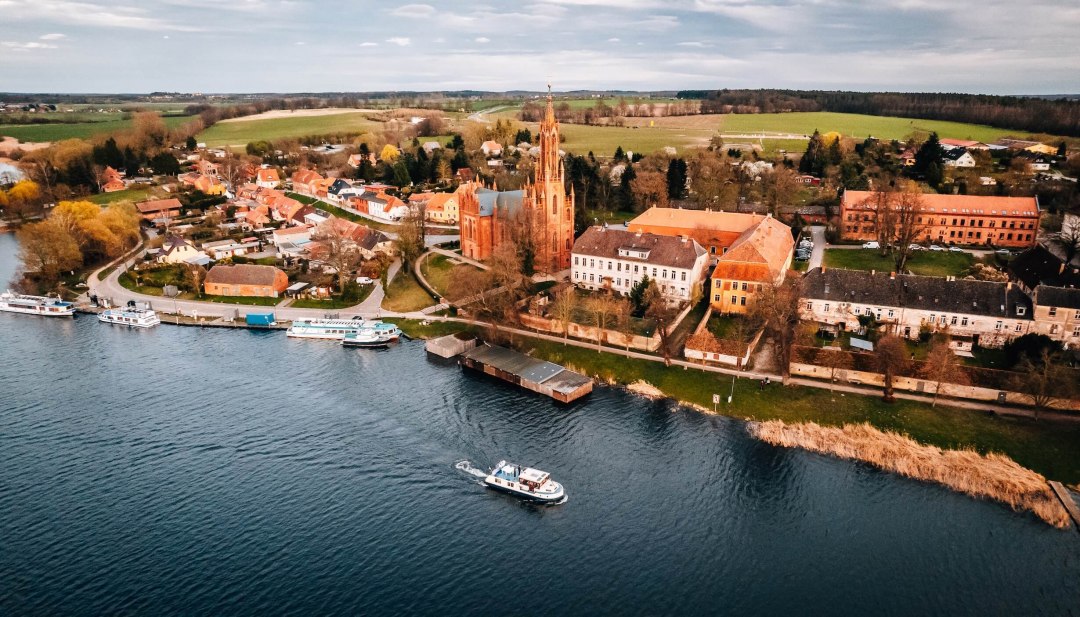 Luftaufnahme mit roter Kirche und Booten am Ufer des Malchower Sees in Mecklenburg-Vorpommern.