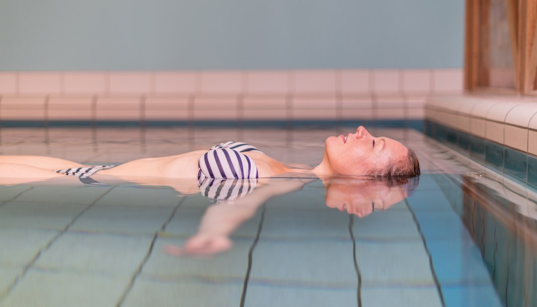 En kvinde slapper af i det termiske saltvandssv&aelig;vebassin i kurcentret i Waren