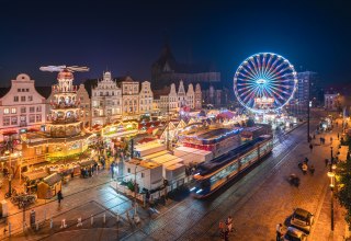 Glinsterende lichtjes en een feestelijke sfeer - de kerstmarkt van Rostock verwent bezoekers met historische gevels, geurige lekkernijen en een stralend reuzenrad in het centrum van de oude stad. // &copy; Erik Gross