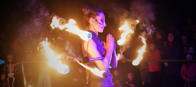 Beim Lampionfest im Zoo Rostock führt eine Frau mit Gesichtsschminke eine Feuershow vor und hält einen brennenden Stab in der Hand. // © Zoo Rostock/ Kloock Beim Lampionfest im Zoo Rostock führt eine Frau mit Gesichtsschminke eine Feuershow vor und hält einen brennenden Stab in der Hand. // © Zoo Rostock/ Kloock