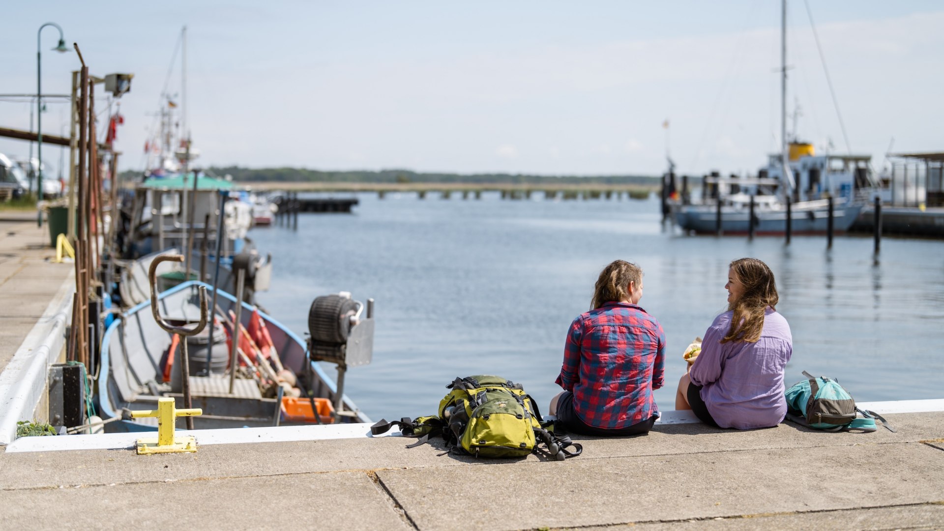 Einmal Fischbrötchen muss sein entlang des Naturparkwegs! Zum Beispiel am Hafen in Altwarp mit Blick übers Wasser. An Rollmops hat sich Linda noch nicht getraut – vielleicht beim nächsten Mal! Diesmal war es ein Backfischbrötchen., © TMV/Gross
