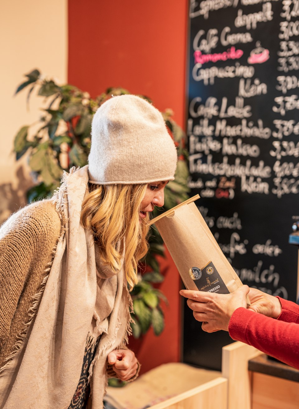 Eine Frau riecht an einer offenen Tüte mit frischem Kaffee - Der Duft von feinen Kaffeebohnen liegt im cafeshop Especial immer in der Luft // Der Duft von feinen Kaffeebohnen liegt im cafeshop Especial immer in der Luft // © MV-T/Tiemann Eine Frau riecht an einer offenen Tüte mit frischem Kaffee - Der Duft von feinen Kaffeebohnen liegt im cafeshop Especial immer in der Luft